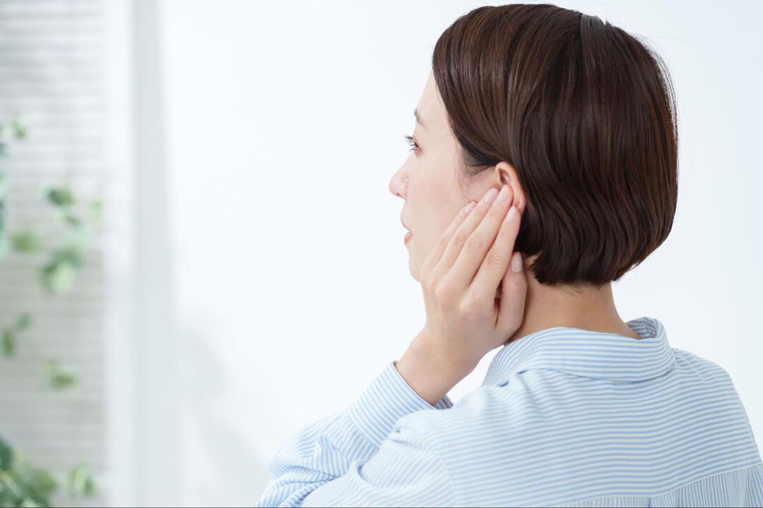 横を向いた女性が、左耳に手を添えている様子