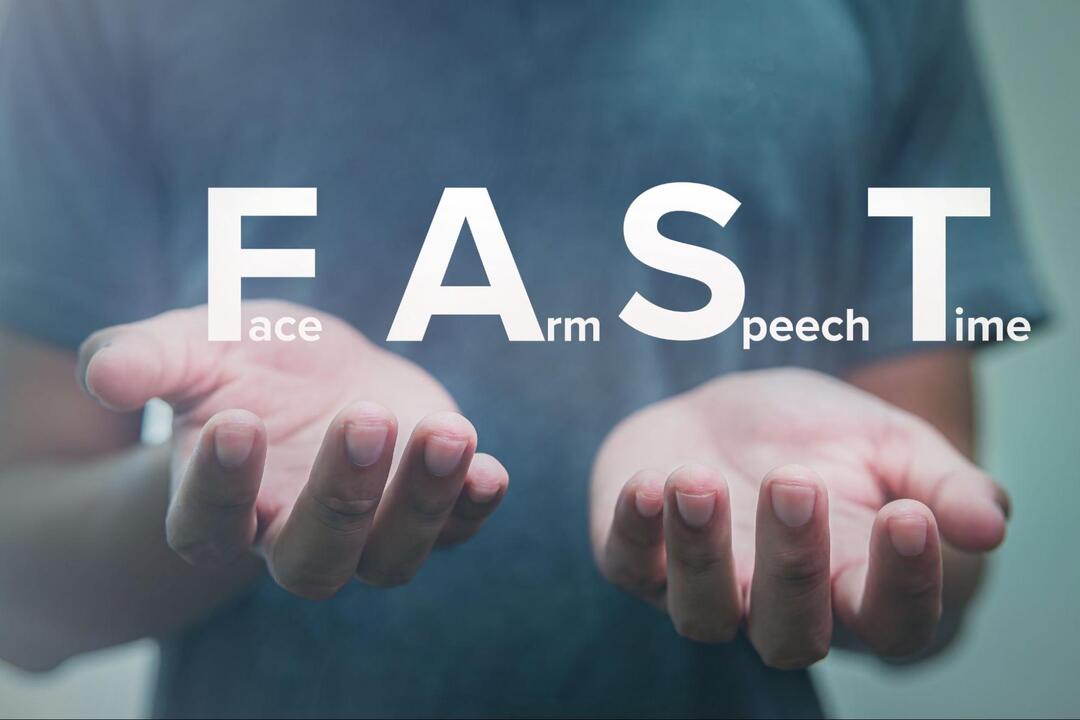 広げた両手の上に、脳梗塞の警告サインである「FAST(Face, Arm, Speech, Time)」の白い文字が浮かび上がっているイメージ