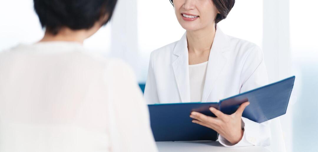 医師が笑みを浮かべながら、対面に座る患者へ説明している様子