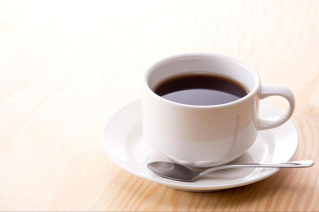 テーブルの上に置かれた白いカップ＆ソーサー入りのブラックコーヒー