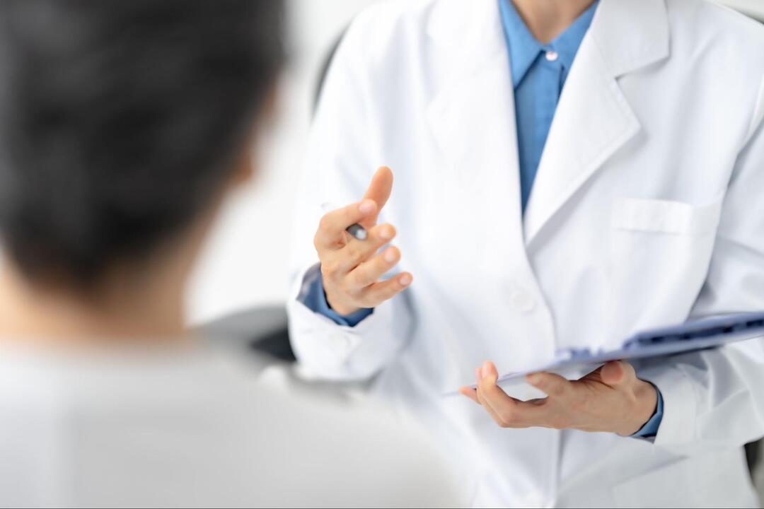 医師が手元にバインダーを持ちながら、ジェスチャーを交えて説明している様子